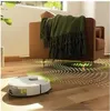 A robot vacuum cleaner is cleaning a wooden floor next to a brown armchair with a green blanket. Anteprima dell’immagine prodotto