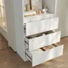 A white bookshelf with three drawers, two of which are open, showing contents. The bookshelf is placed on a wooden floor. Produktbild-Vorschau