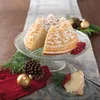 A Bundt cake shaped like a pine forest, dusted with powdered sugar, sits on a cake stand, decorated for Christmas with pine sprigs, pinecones, and ornaments. Anteprima dell’immagine prodotto