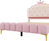A close-up side view of a pink upholstered bed frame with a tufted headboard and a crown detail. Podgląd zdjęcia produktu
