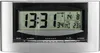 A digital alarm clock with a silver frame and a black face displaying the time, date, and temperature. Náhľad obrázku produktu
