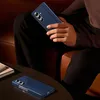A person is holding a blue foldable smartphone while sitting on a couch. Another phone is on a table in the foreground. Anteprima dell’immagine prodotto