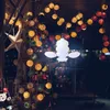 A display of decorative string lights, possibly at a market or festival, with a central white lantern-like light fixture. Anteprima dell’immagine prodotto