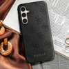 A close-up shot of a phone case with a Guess logo, placed on top of a book and fabric. Produktbild-Vorschau