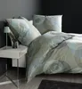A bed with bedding and pillows, a bedside table with a lamp and a vase of flowers. Voir les images du produit