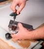 A person's hands are using a T-handle hex wrench to adjust a tool, likely a router or planer, on a wooden surface. Anteprima dell’immagine prodotto