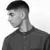 A black and white profile shot of a man with a fade haircut and a dark collared shirt. Anteprima dell’immagine prodotto