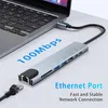 A laptop connected to a multi-port adapter hub with an Ethernet cable plugged in. Produktbild-Vorschau