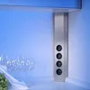 A vertical power strip with four outlets is shown in a kitchen setting, with wine glasses and grapes in the foreground. Produktbild-Vorschau