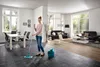 A woman is mopping the floor in a modern living and dining room. Produktbild-Vorschau