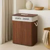 A laundry basket with two compartments is shown in a room with curtains and decorative items. Produktbild-Vorschau