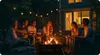 A group of friends are gathered around a fire pit in a backyard at night, roasting marshmallows and playing guitar. Náhľad obrázku produktu