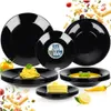 A collection of black dinnerware, including plates and bowls, arranged with food items like pasta and cake, and decorative elements like fruits and vegetables. Anteprima dell’immagine prodotto