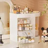 A white makeup organizer filled with various cosmetic products sits on a desk, with a mirror and a decorative mannequin in the background. Náhled obrázku produktu