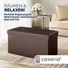 A brown storage ottoman is placed in a living room setting with a sofa and side table in the background. Anteprima dell’immagine prodotto
