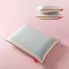 Three pillows are shown against a pink background. One pillow is in the foreground, angled diagonally, and two pillows are stacked on top of each other in the background. Produktbild-Vorschau