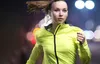 A woman running at night with blurred city lights in the background. Voir les images du produit