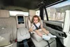 A young child sits in a car seat in the back of a luxury vehicle. Voir les images du produit