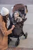 A woman is adjusting a baby in a stroller. Náhled obrázku produktu
