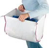 A person is holding a white laundry basket with pink trim, filled with blue laundry. Produktbild-Vorschau