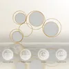A decorative metal wall mirror with multiple circular frames and mirrors, displayed against a neutral background with reflective elements below. Produktbild-Vorschau