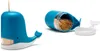 A blue whale-shaped toothpick dispenser is shown on the left, with a toothpick sticking out of its top. On the right, the dispenser is shown open, revealing a pile of toothpicks inside, with its white tail piece detached. Náhled obrázku produktu