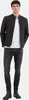 A man wearing a black jacket, white t-shirt, and dark jeans, standing against a white background. Produktbild-Vorschau