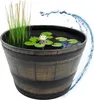 A decorative barrel planter filled with water, lily pads, a water lily, and reeds, with a splash of water on the side. Anteprima dell’immagine prodotto