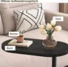 A close-up of a modern coffee table with decorative items on it, placed next to a sofa. Produktbild-Vorschau