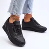 A person's legs wearing ripped jeans and black sneakers. Produktbild-Vorschau