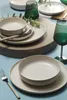 A table setting with plates, bowls, cutlery, and a wine glass. Voir les images du produit