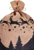 A close-up view of the top of a burlap Christmas sack with a drawstring closure. The sack is decorated with a black silhouette of reindeer pulling a sleigh, snowflakes, and pine trees along the bottom edge. Anteprima dell’immagine prodotto