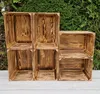 A set of wooden crates stacked against a green leafy background. Produktbild-Vorschau
