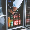 A person is reaching into a cooler to grab a bottle of drink. Náhled obrázku produktu
