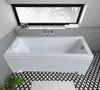 A modern white bathtub in a bathroom with a large window and patterned tiles. Produktbild-Vorschau