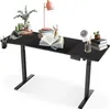 A black adjustable height desk with various office supplies on top.