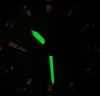Close-up of a watch face in the dark, with luminous hands and markers. Voir les images du produit