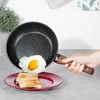 A hand is holding a frying pan with a fried egg over a plate of toast. Anteprima dell’immagine prodotto