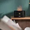 A black aroma diffuser with a flame effect sits on a wooden nightstand next to some books. Voir les images du produit