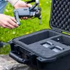 A person is holding a drone over an open case with foam inserts. Produktbild-Vorschau