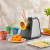 A Zilan electric grater is shown on a countertop, with carrots being grated into a pile on a plate. Several attachments and sliced lemons and cucumbers are also visible. Anteprima dell’immagine prodotto