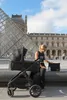 A woman with a stroller in front of the Louvre Pyramid in Paris. Produktbild-Vorschau