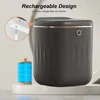 A dark gray smart trash can with a gold trim is shown on a white pedestal, with a close-up inset showing a charging mechanism and a battery icon. Produktbild-Vorschau