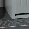 A close-up view of the bottom corner of a gray cabinet or shoe rack, resting on a dark, textured surface. Náhled obrázku produktu