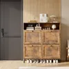 A shoe cabinet with shoes on the floor in front of it, next to a door and a wall with vertical wooden slats. Produktbild-Vorschau