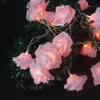 A string of pink rose-shaped LED lights intertwined with green foliage. Produktbild-Vorschau