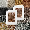 Two white plastic containers of epoxy resin are placed in the center of the image, surrounded by a collage of different colored gravel and stone aggregates. The containers have labels with product information and images of the gravel. Produktbild-Vorschau