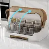 A dish drying rack with cups and cutlery inside, set on a kitchen counter. Blue arrows indicate airflow. Produktbild-Vorschau