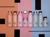 A collection of reusable water bottles in various sizes and colors arranged on a split-color background. Produktbild-Vorschau