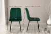 Two views of a green velvet chair with dimensions indicated by lines and text. The background is a plain wall with some decorative branches in a vase on the right. Anteprima dell’immagine prodotto